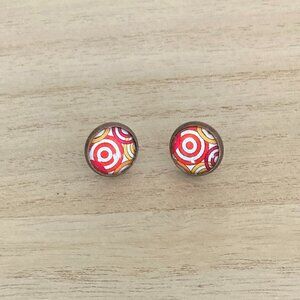 Stud earrings. Glass dome over a red, yellow and white pattern.
